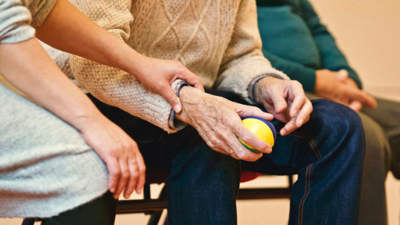 A therapist provides disability support in Townsville by helping an older person use a therapy device.